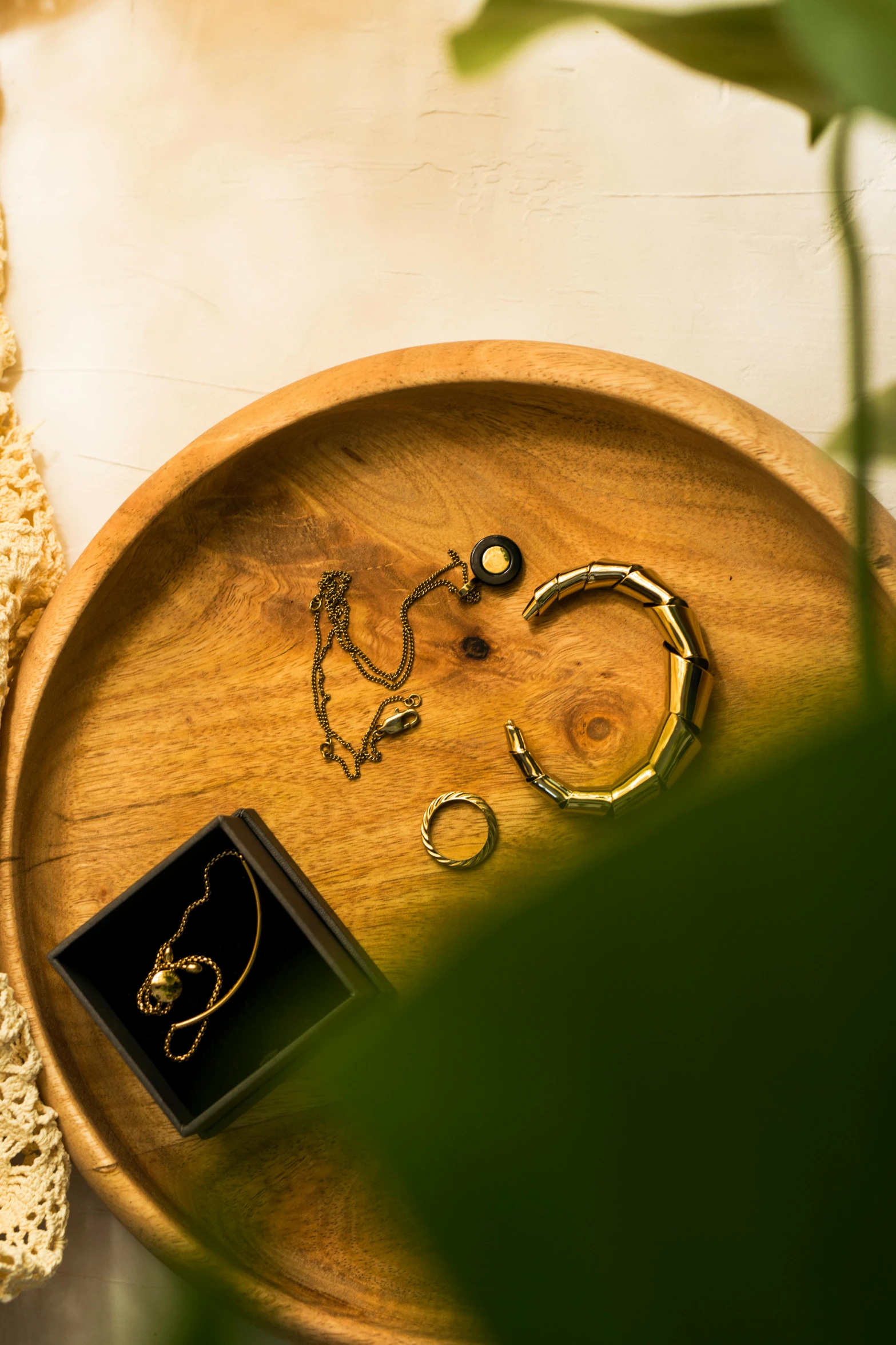 a wooden tray filled with jewelry on top of a table, a still life, inspired by Ruth Jên, trending on pexels, minimalism, shot at golden hour, indonesia, top down shot, circular