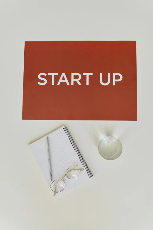 a notepad sitting on top of a desk next to a cup of coffee, a picture, graffiti, ai startup, high resolution print :1 red, up, set against a white background