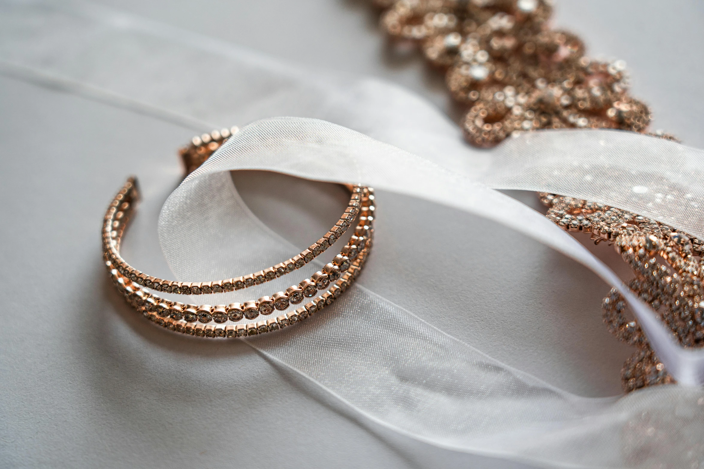 a pair of gold bracelets sitting on top of a white cloth, by Emma Andijewska, pexels contest winner, intricate copper details, ribbon, sparkling, thumbnail