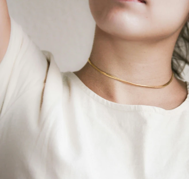 a woman in a white shirt is brushing her hair, an album cover, by Nina Hamnett, trending on unsplash, gold necklace, thick collar, thin porcelain, ochre