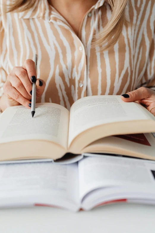 a woman sitting at a table with an open book and a pen in her hand, curated collections, multiple stories, helpful, trending photo