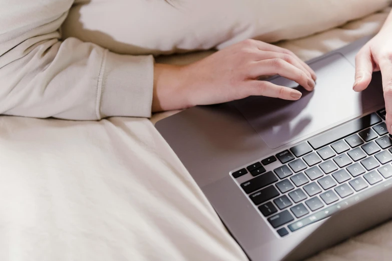 a woman using a laptop computer on a bed, pexels, subtle detailing, rounded lines, brown, thumbnail