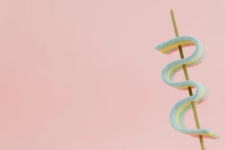 a close up of a candy snake on a stick, by Emma Andijewska, trending on pexels, magic realism, pastel faded grey rainbow, background image, miniature product photo, dessert