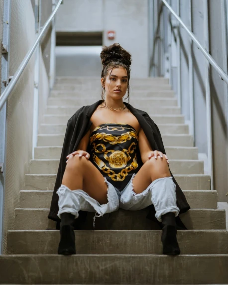 a woman sitting on top of a set of stairs, an album cover, inspired by Rowena Meeks Abdy, trending on pexels, renaissance, cyborg fashion model, macho pose, madison beer, golden corset