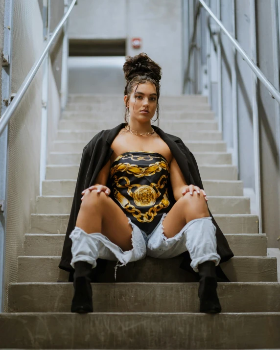 a woman sitting on top of a set of stairs, an album cover, inspired by Rowena Meeks Abdy, trending on pexels, renaissance, cyborg fashion model, macho pose, madison beer, golden corset