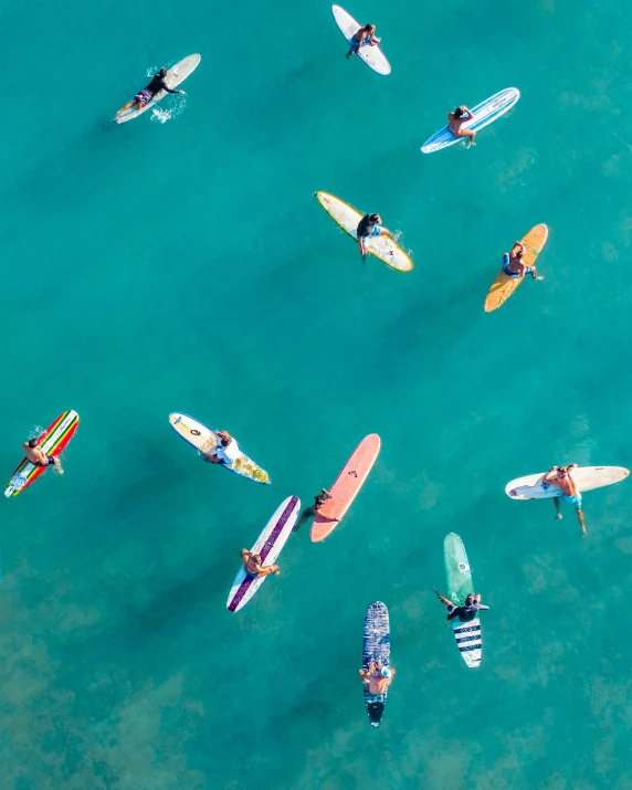 a group of people riding surfboards on top of a body of water, from above