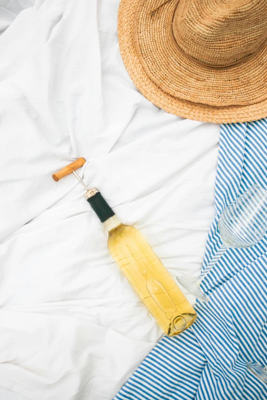 a straw hat sitting on top of a bed next to a bottle of wine, pexels contest winner, wearing white pajamas, stripes, yellow clothes, white background