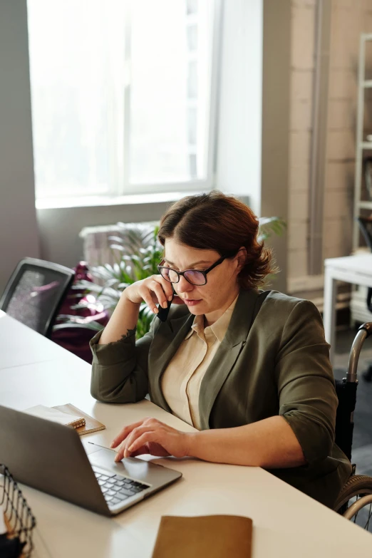 a woman sitting at a desk using a laptop computer, pexels, girl making a phone call, low quality photo, thumbnail, serious business