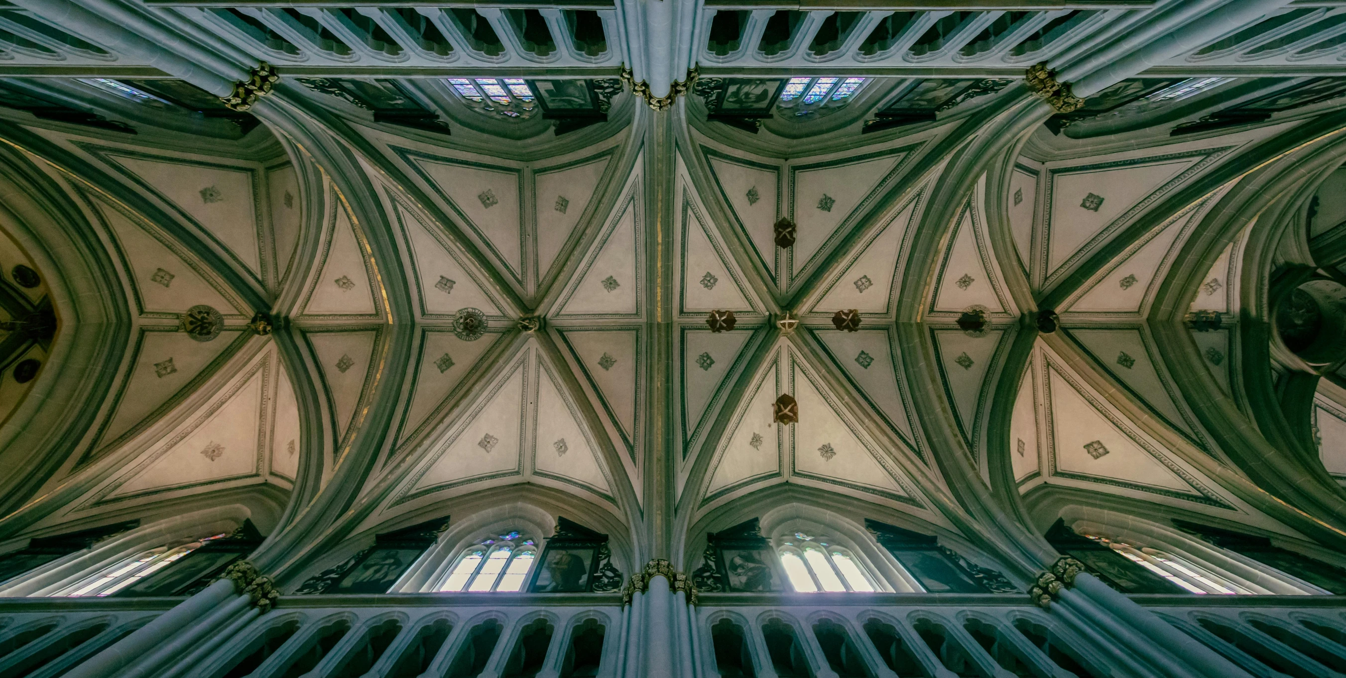 a view up into the ceiling of a cathedral, an album cover, unsplash contest winner, symmetrical faces, many large green windows, 14th century, high - angle view