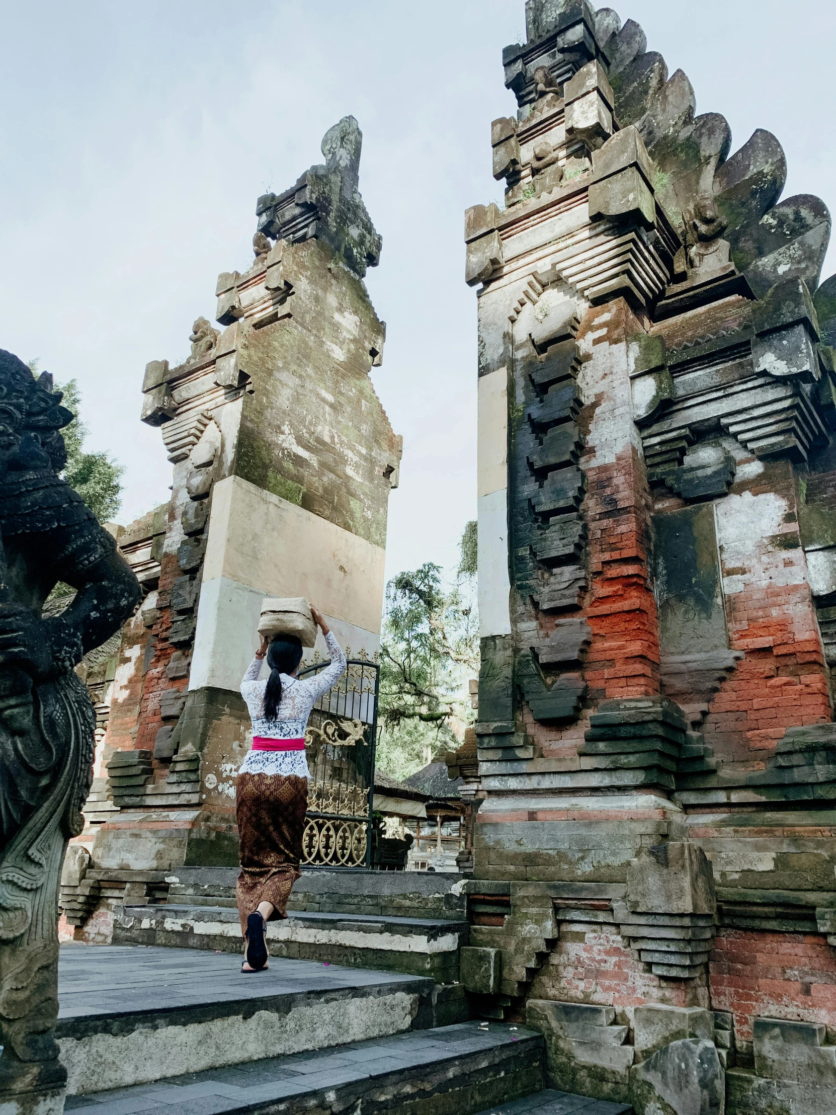 a woman walking up the steps of a temple, a statue, inspired by I Ketut Soki, ruins around, 📷 mungojerrie and rumpleteazer, preserved historical, standing astride a gate