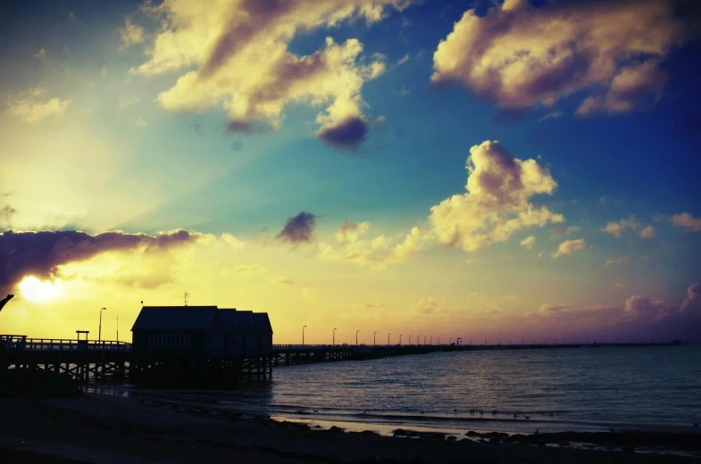 a pier that is next to a body of water, pexels contest winner, yellow clouds, medium format, hut, vintage glow