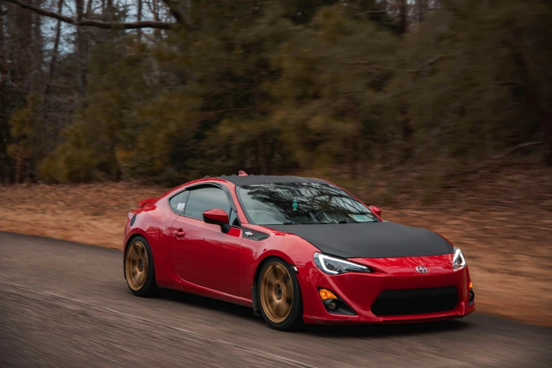 a red sports car driving down a road, a portrait, by Austin English, pexels contest winner, ae 8 6, red gold black, full - body - front - shot, merged