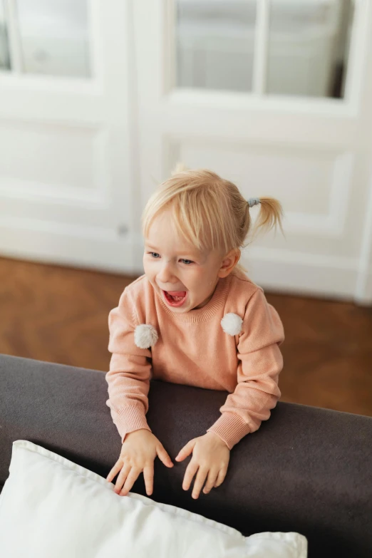 a little girl sitting on top of a couch next to a pillow, pexels contest winner, happening, spitting cushions from his mouth, puff sleeves, ekaterina, screeching