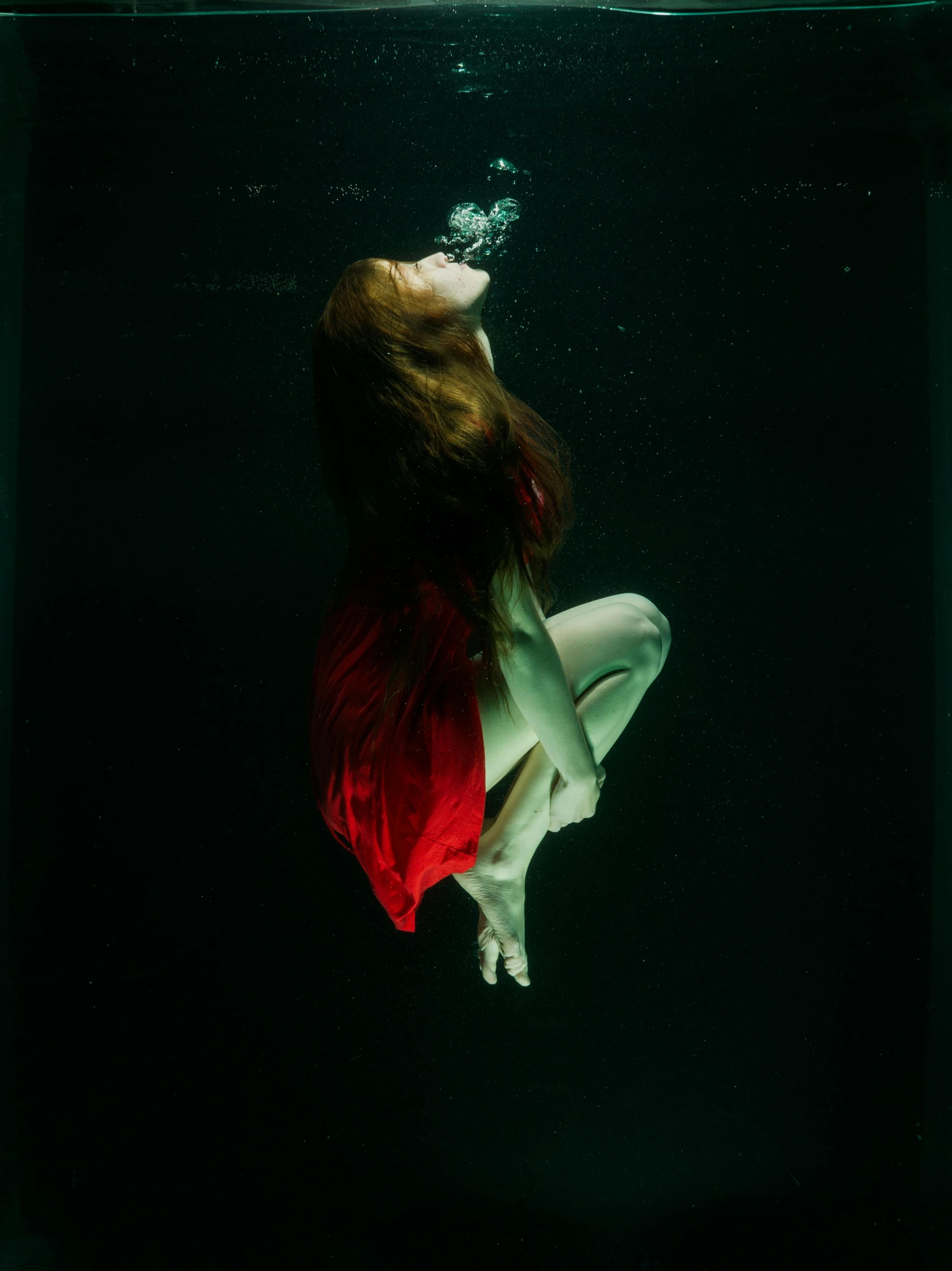 a woman in a red dress swimming under water, an album cover, inspired by Brooke Shaden, unsplash contest winner, renaissance, ignant, dark green water, looking sad, red and cyan