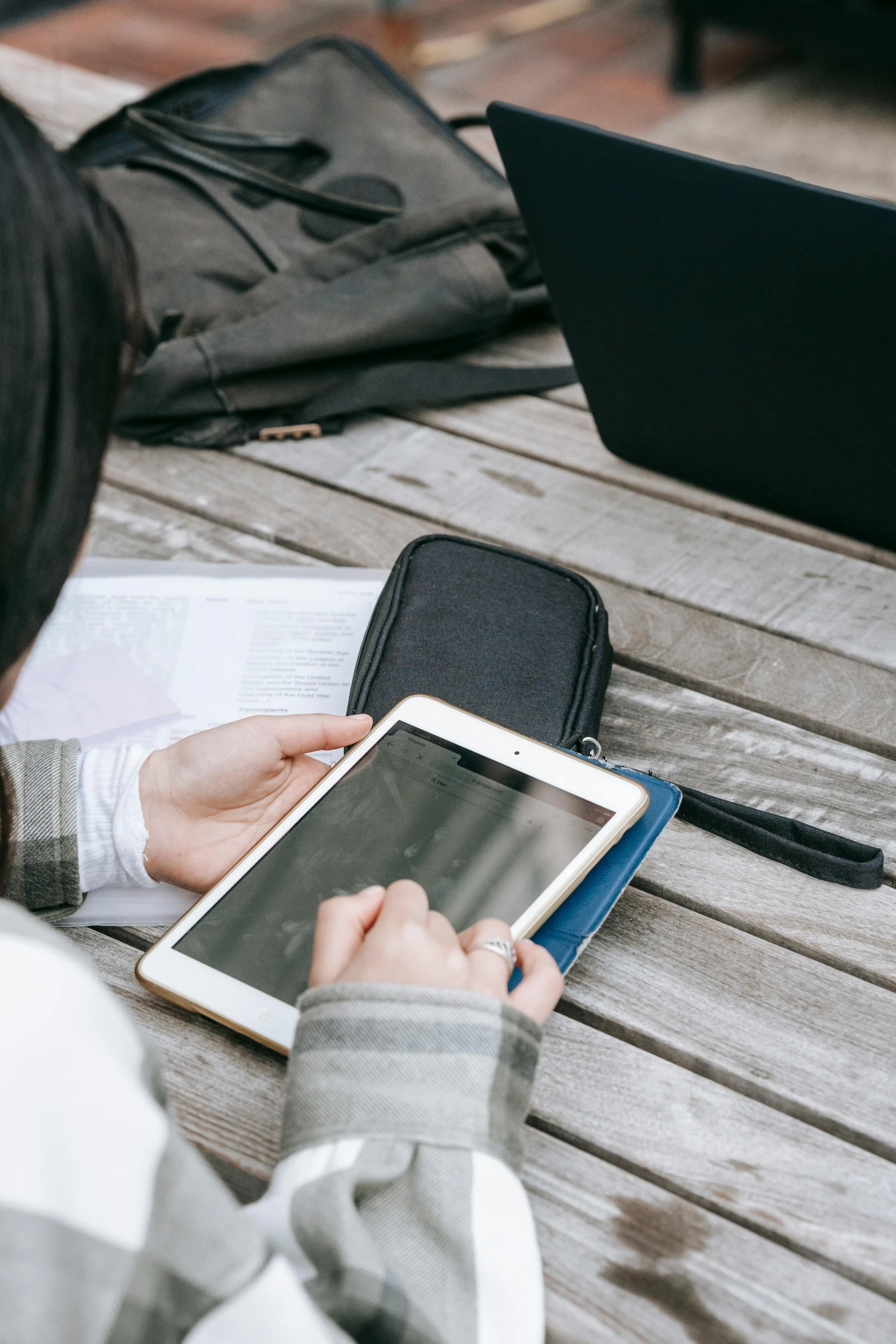 a woman sitting at a table using a tablet computer, by Carey Morris, trending on unsplash, leather pouch, outside on the ground, praying, holding a briefcase