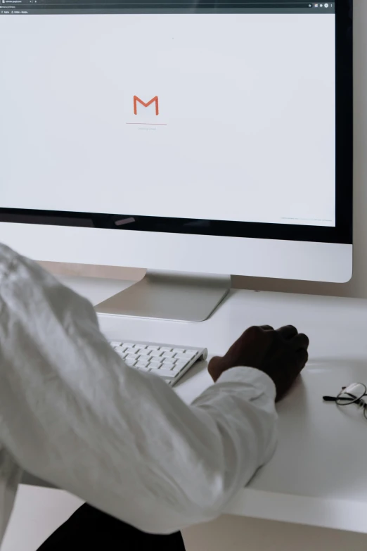 a man sitting at a desk in front of a computer, by Carey Morris, trending on pexels, minimalistic logo, email, glossy white metal, google design