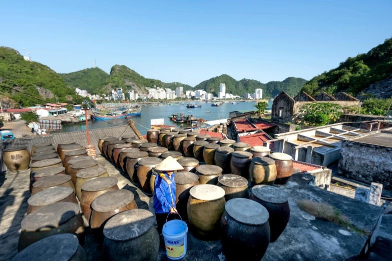 a group of barrels sitting on top of a roof next to a body of water, pexels contest winner, ao dai, harbour, avatar image, cooking oil