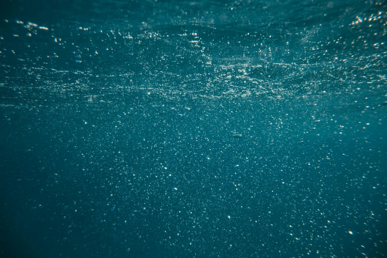 a body of water with bubbles coming out of it, inspired by Elsa Bleda, unsplash, hurufiyya, swimming underwater, prussian blue, ground level shot, sparkly