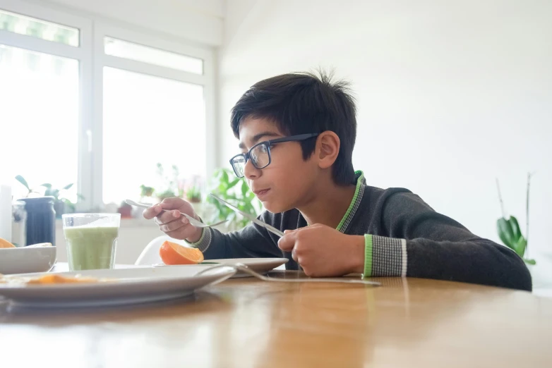 a young boy sitting at a table with a plate of food, wearing medium - sized glasses, connectivity, avatar image, best shot