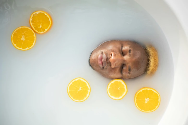 a man laying in a bath filled with orange slices, inspired by Carrie Mae Weems, process art, healing pods, perfect facial symettry, with lemon skin texture, floating crown