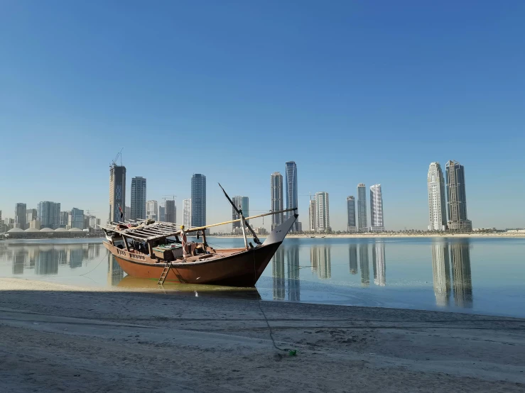 a boat sitting on top of a beach next to a body of water, pexels contest winner, hurufiyya, arab ameera al-taweel, tall buildings in background, thumbnail, hd footage