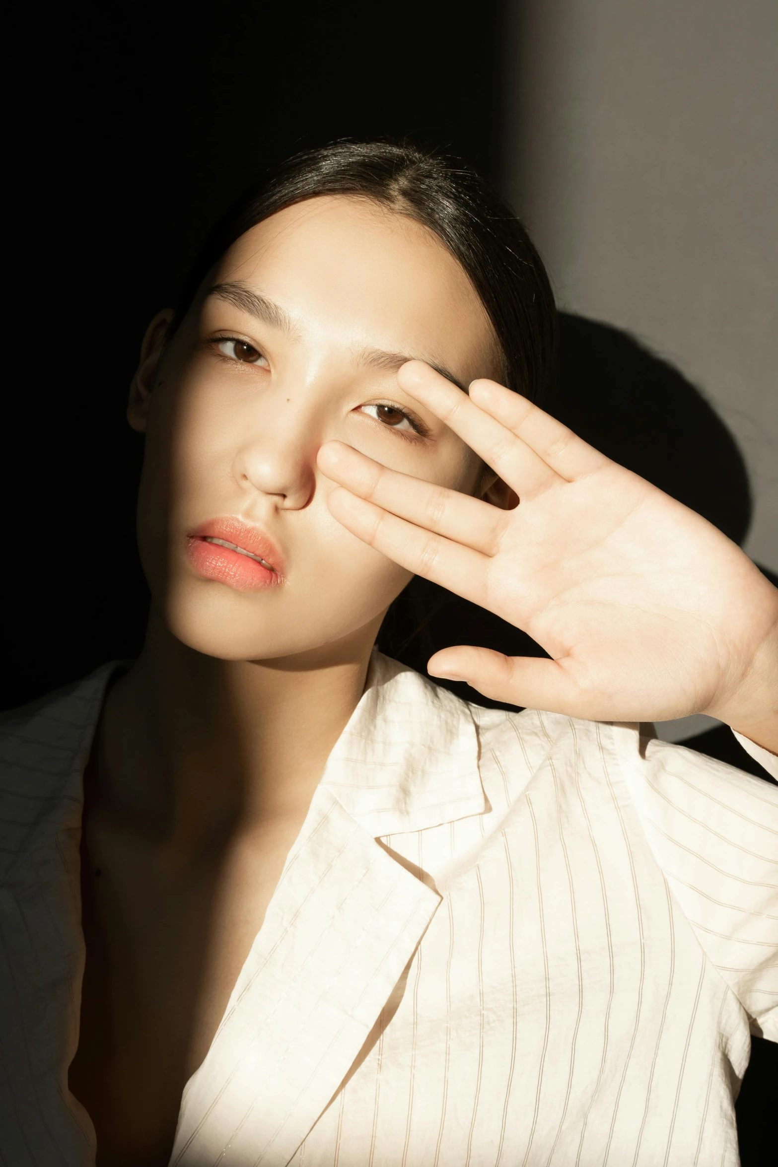 a woman covering her eyes with her hands, an album cover, inspired by Kim Tschang Yeul, unsplash, photorealism, fashion model face, sleek hands, half asian, play of light