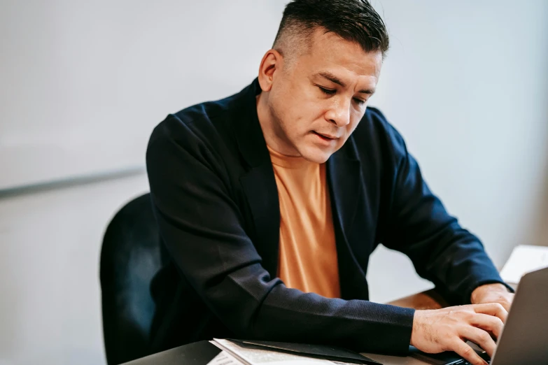 a man sitting at a desk using a laptop computer, tony taka, profile image, temuera morrison, worksafe. instagram photo