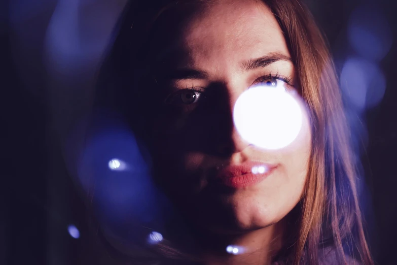a close up of a woman's face with lights in the background, pexels contest winner, light and space, lens orbs, with blue light inside, analogue photo low quality, instagram picture