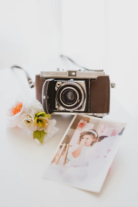 a camera sitting on top of a table next to a flower, a polaroid photo, portrait n - 9, wedding photo, full product shot, brown ) )