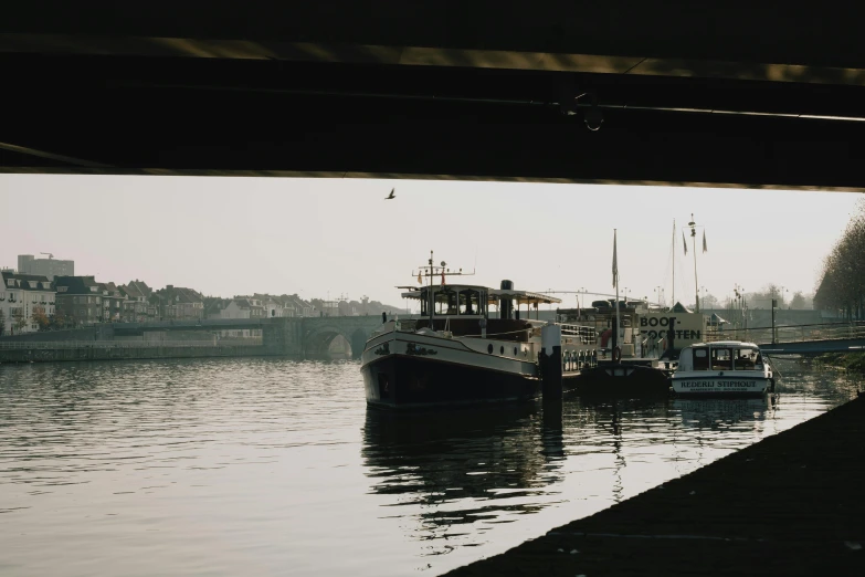 a couple of boats that are sitting in the water, pexels contest winner, under bridge, hard morning light, low quality footage, trending on vsco