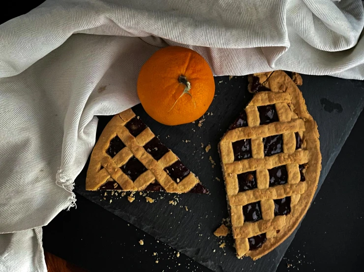 a couple of pies sitting on top of a cutting board, a still life, inspired by Richmond Barthé, reddit, hurufiyya, dark blue + dark orange, stroopwaffel, trick or treat, the photo shows a large