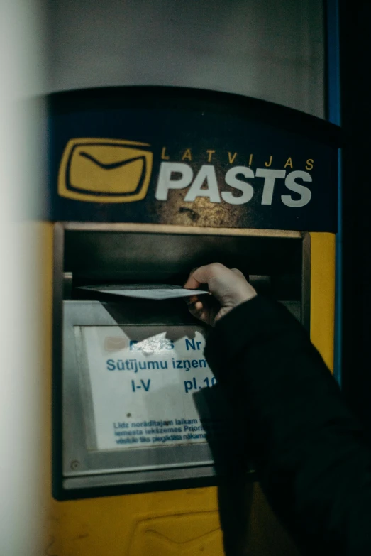 a person inserting a piece of paper into an atm machine, by Julia Pishtar, pexels contest winner, capital of estonia, delivering mail, full pallet image, 🚿🗝📝