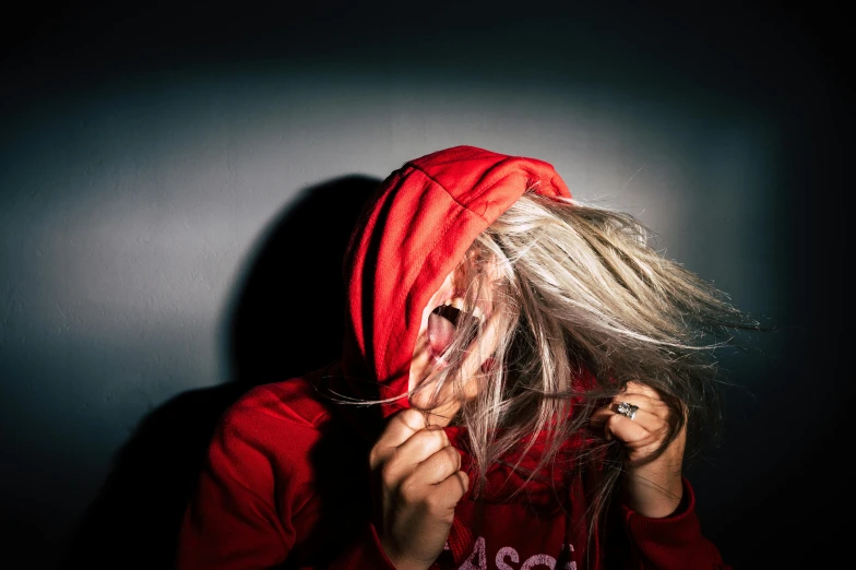 a woman with a red hoodie covering her face, an album cover, inspired by Elsa Bleda, trending on pexels, hyperrealism, silver hair girl, headbanging, high-contrast lighting, disheveled