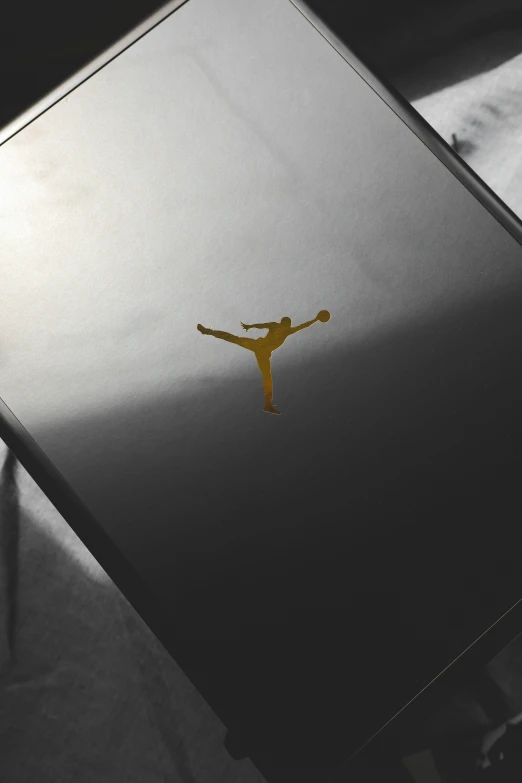 a laptop computer sitting on top of a bed, an album cover, inspired by Jordan Grimmer, unsplash contest winner, nba logo, shiny silver with gold trim, mortal kombat 11, bottom view