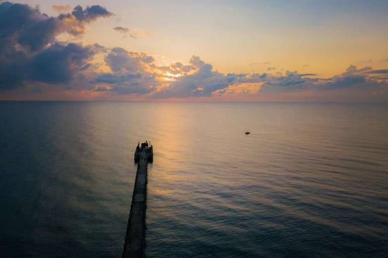 a pier in the middle of the ocean at sunset, by Brad Holland, black sea, 2022 photograph, wide high angle view, conde nast traveler photo