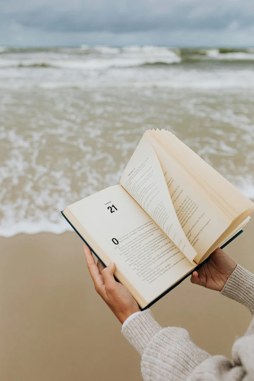 a woman reading a book on the beach, by Carey Morris, pexels contest winner, vertical orientation, unreadable text, stand up with the sea behind, detail shot