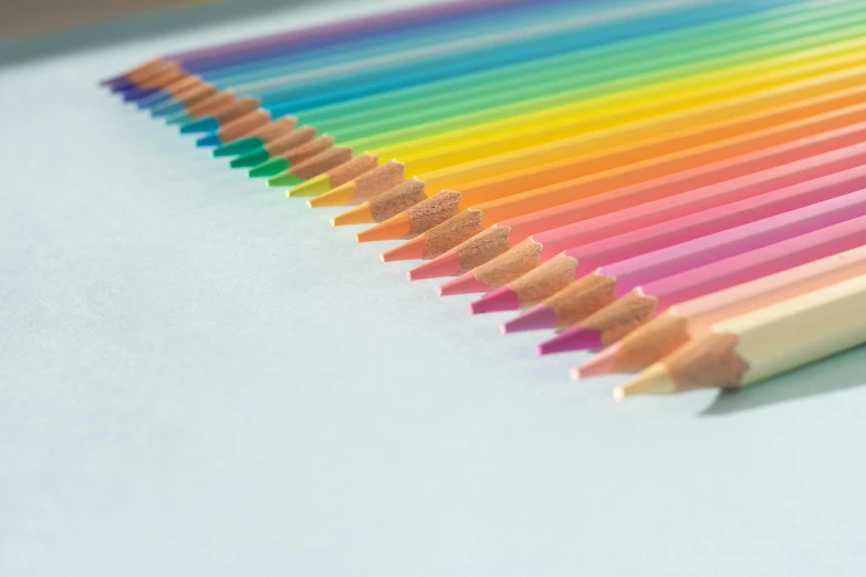 a group of colored pencils sitting on top of a table, a pointillism painting, by Rachel Reckitt, trending on pexels, pale pastel colours, close up shot from the side, teal and orange colours, rainbow neon strips