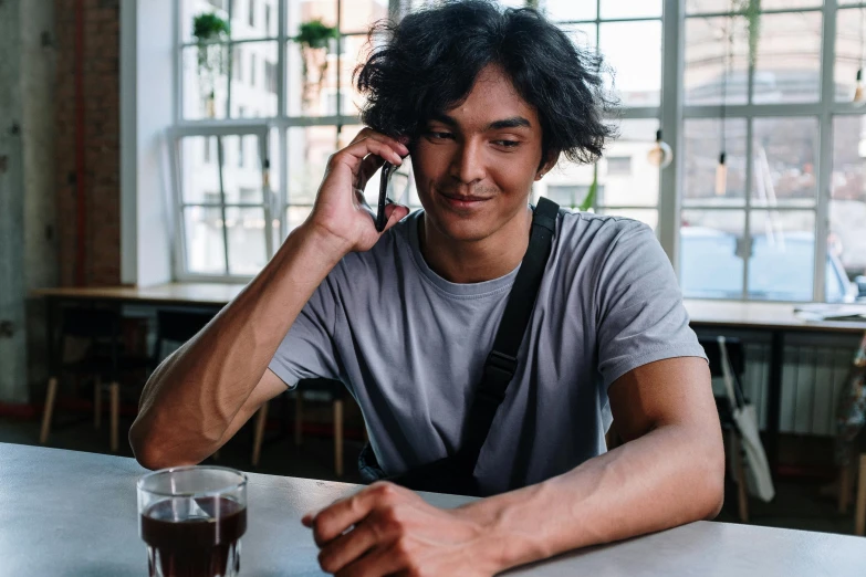 a man sitting at a table talking on a cell phone, trending on pexels, hyperrealism, aboriginal australian hipster, androgynous person, self - satisfied smirk, asian human