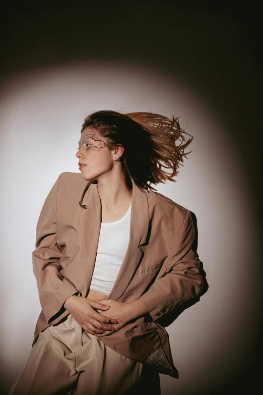 a woman with her hair blowing in the wind, an album cover, by Carey Morris, trending on pexels, renaissance, wearing a worn out brown suit, portrait sophie mudd, white jacket, dark backdrop