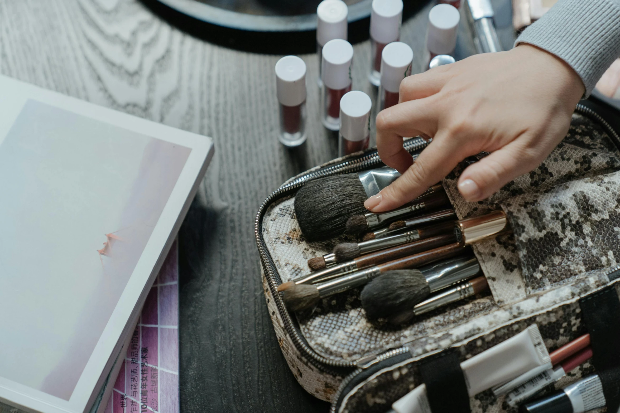 a close up of a person putting makeup in a case, a photorealistic painting, trending on pexels, tachisme, brushes, on a table, textured base ; product photos, colourised