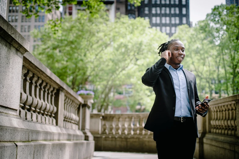 a man in a suit talking on a cell phone, a photo, inspired by William H. Mosby, pexels contest winner, in a city park, emmanuel shiru, alana fletcher, walking to the right