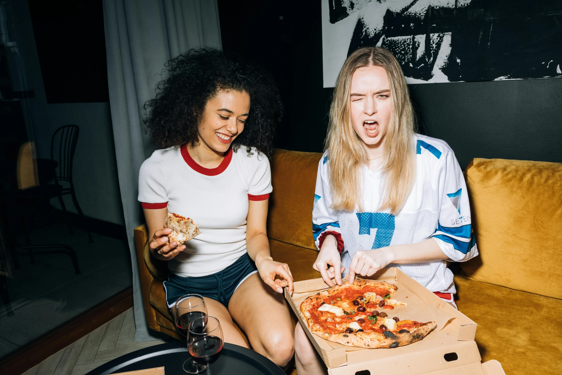 two women sitting on a couch eating pizza, by Julia Pishtar, pexels contest winner, sophie turner girl, nightlife, tessa thompson, eating a pizza margherita