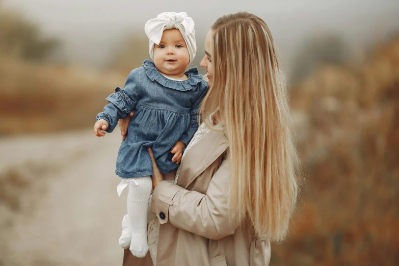 a woman holding a baby in her arms, pexels contest winner, beautiful blonde girl, thumbnail, denim, elegantly dressed