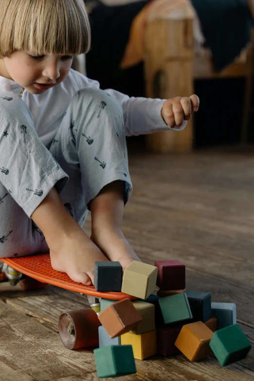 a little boy that is sitting on a skateboard, pexels contest winner, visual art, wooden art toys on base, building blocks, grey, slate