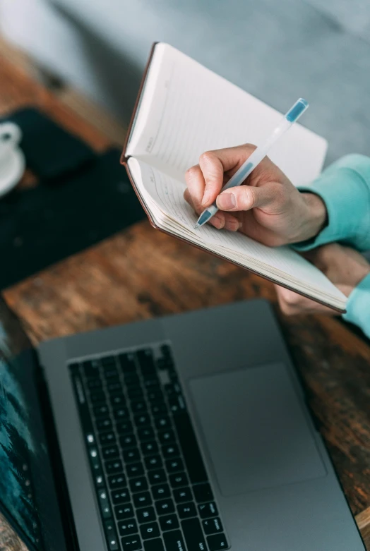 a woman writing in a notebook next to a laptop, thumbnail, center of image, multiple stories, fully functional