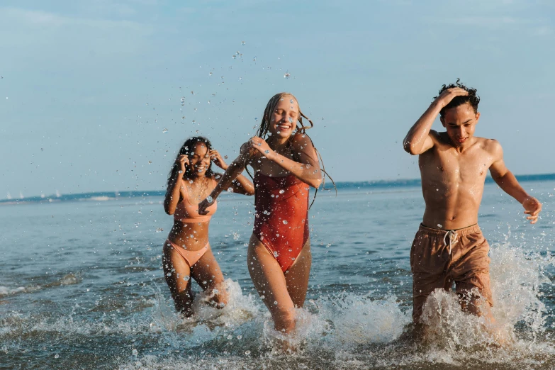 a group of people that are standing in the water, playing at the beach, profile image