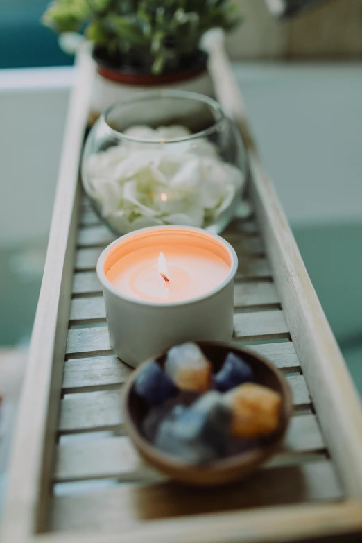 a row of candles sitting on top of a wooden tray, light and space, bubble bath, curated collections, half image, sunset mood