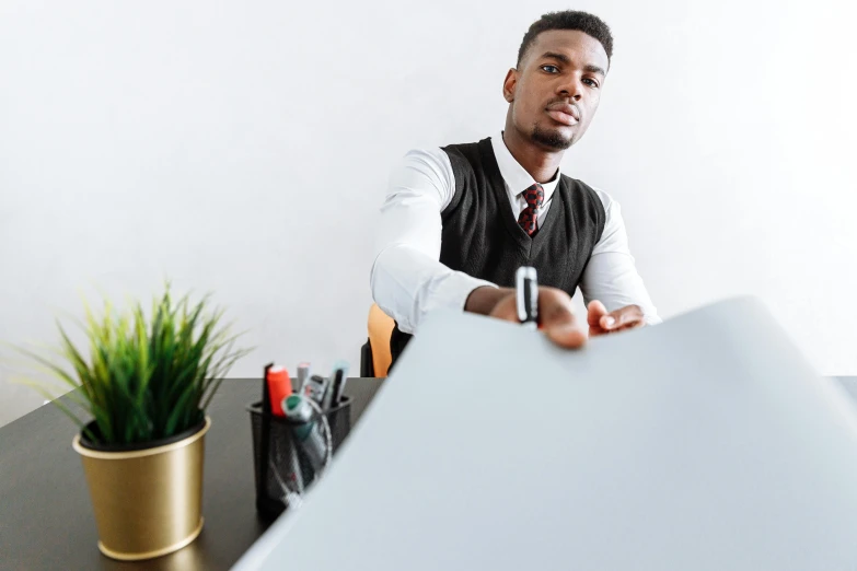 a man sitting at a desk with a pen in his hand, pexels contest winner, whiteboards, man is with black skin, wearing a shirt with a tie, large format picture