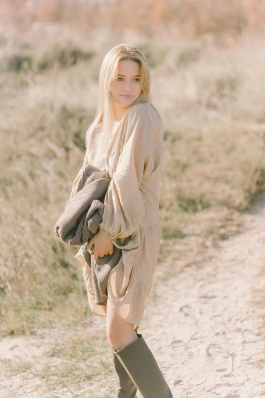 a woman standing in the middle of a dirt road, boho neutral colors, photo of margot robbie, medium format. soft light, promo image