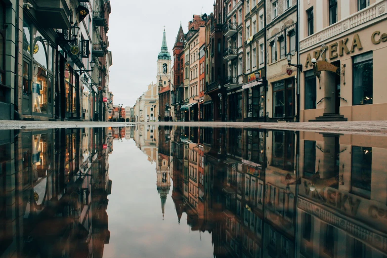 a puddle of water in the middle of a city street, by Emma Andijewska, unsplash contest winner, square, zdzisław, waterways, 2 0 0 0's photo